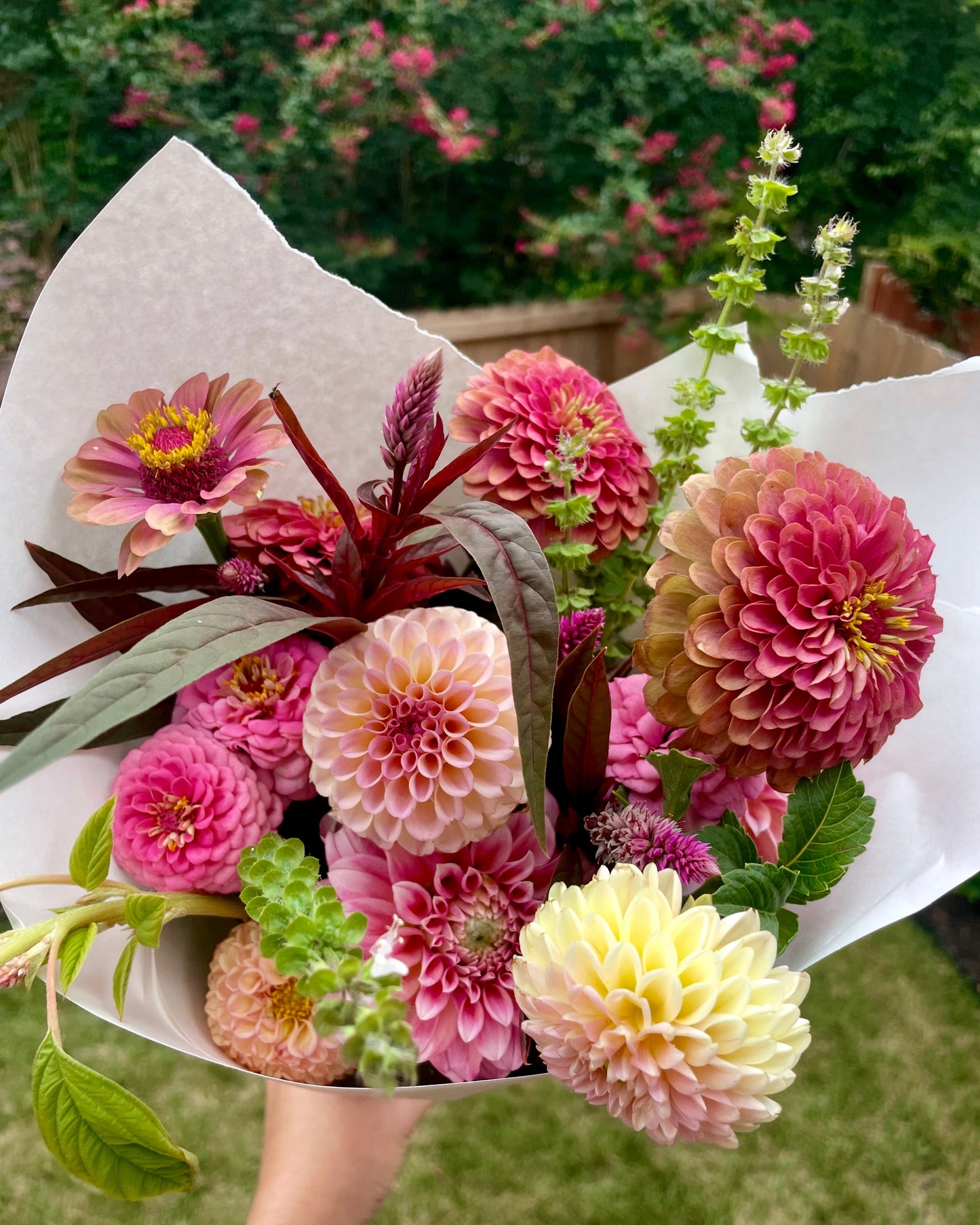 Bouquet of colorful flowers held by a person with a blurred green background